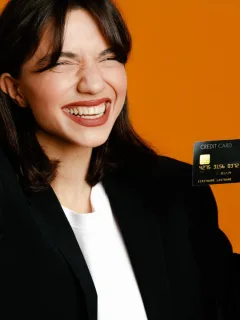 A happy woman holding her Discover it Secured credit card.
