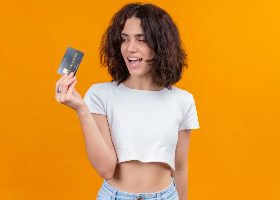 A girl holding her Wells Fargo Active Cash credit card.