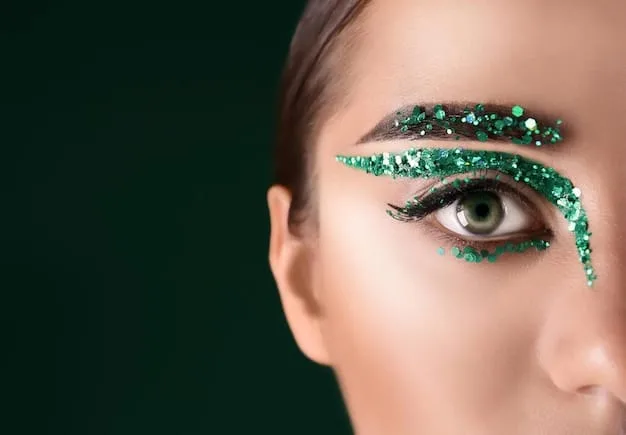 A detailed makeup artist's hand applying a precise line of sparkly green eyeliner to a model's upper lash line, showcasing artistic skill and the use of color beyond traditional black or brown.