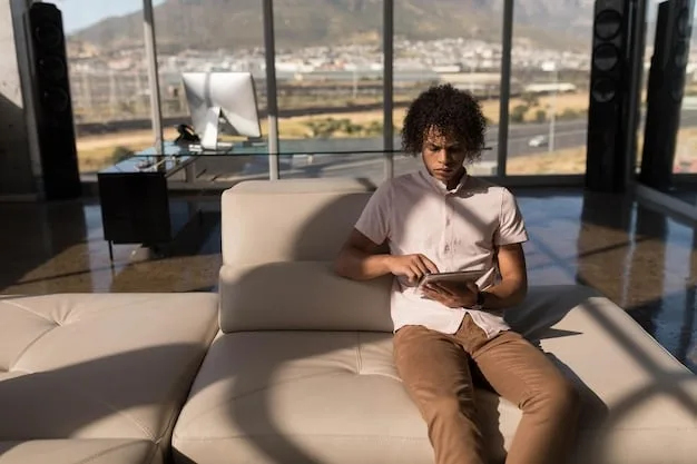 A person using a laptop comfortably in a well-lit, modern airport lounge, surrounded by minimalist decor and other relaxed travelers.