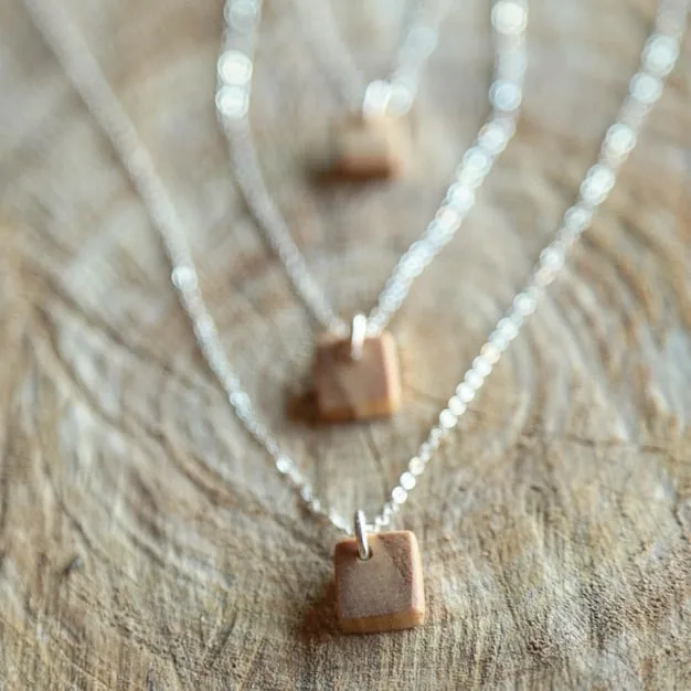 A delicate necklace with a lab-grown diamond pendant, resting on a sustainably sourced wooden display, emphasizing ethical and eco-conscious jewelry choices. Soft, natural lighting.