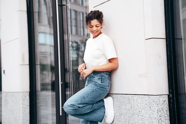 A casual chic outfit featuring a white organic cotton t-shirt, high-waisted ethical denim jeans, and comfortable sustainable sneakers. The setting is a bright, airy coffee shop.