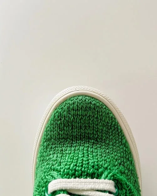 A close-up shot of a pair of sustainable sneakers, highlighting textured materials like recycled knit fabric and plant-based leather, with a subtle natural color palette.