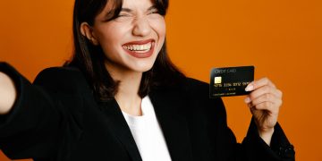 A happy woman holding her Discover it Secured credit card.