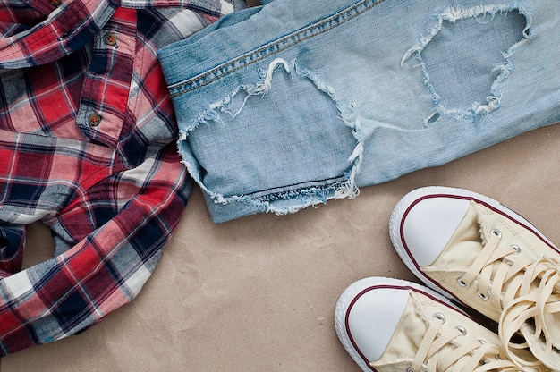 A detailed flat lay of a perfectly worn-in pair of medium-wash straight-leg jeans with a simple white T-shirt and classic leather belt, emphasizing versatility.