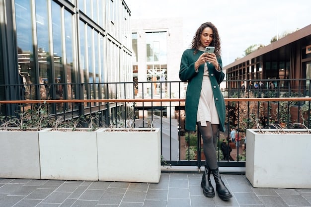 A woman in a long, flowing grey tunic sweater over black leggings, paired with sleek black ankle boots and a minimalist necklace, walking purposefully in a modern city setting at an outdoor cafe.