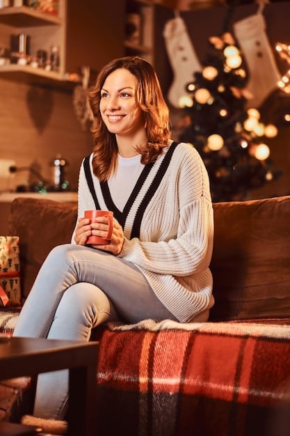 A woman subtly smiling, wearing a soft cashmere sweater tucked into a flowing pleated midi skirt, at a cozy, dimly lit indoor cafe, holding a coffee cup.