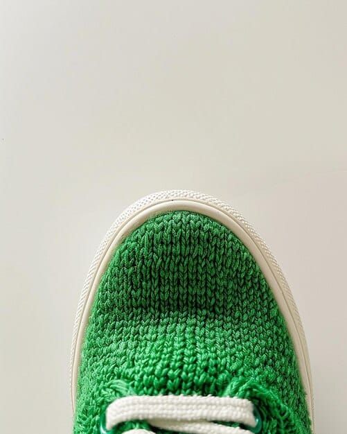 A close-up shot of a pair of sustainable sneakers, highlighting textured materials like recycled knit fabric and plant-based leather, with a subtle natural color palette.