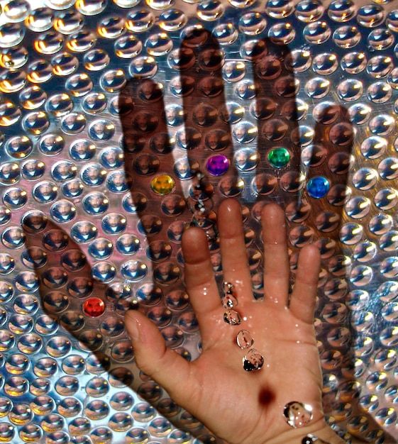 A detailed close-up shot of hands adorned with multiple chunky retro rings and bracelets, some with colorful gemstones, showcasing diverse textures and designs.