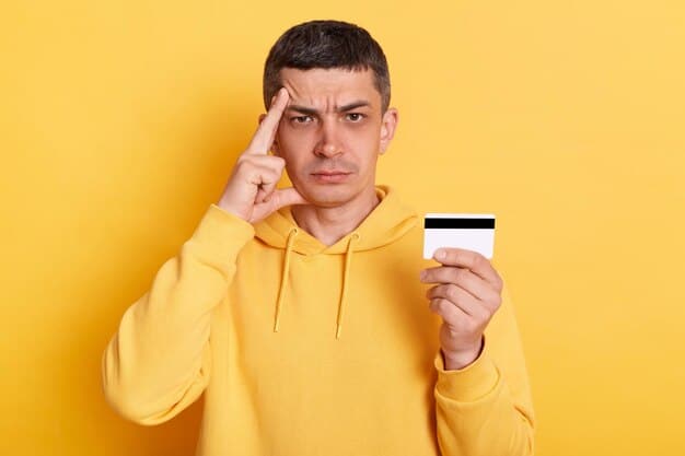 A person's hand holding a single credit card, with a slightly worried or thoughtful expression, over a blurred background of daunting financial documents or bills, suggesting the need for careful consideration.